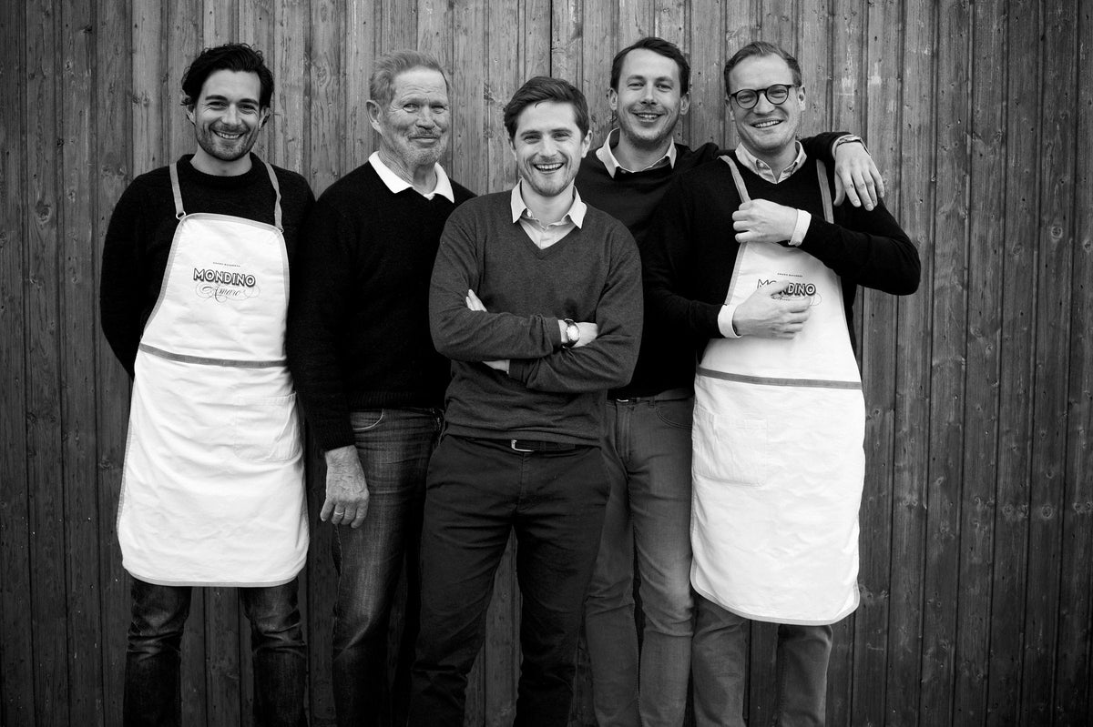 Das Mondino-Team in Schürzen vor einer Holzwand