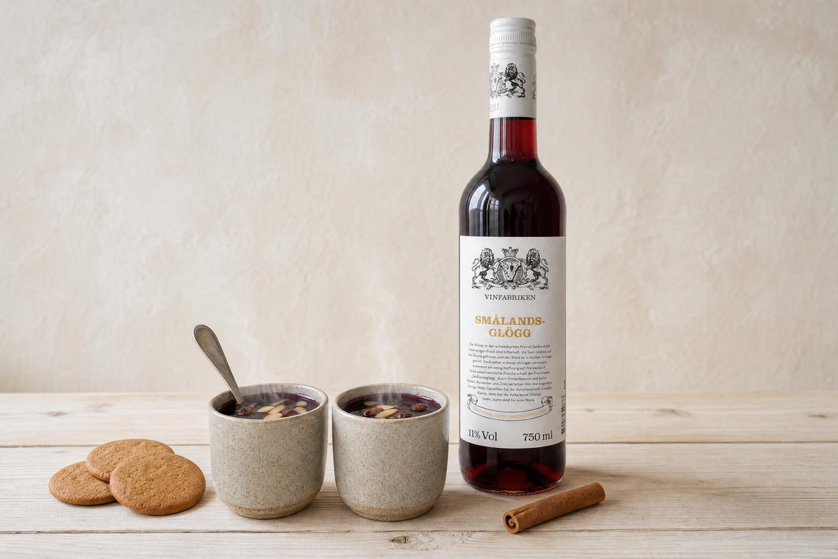 Zwei Becher Glögg mit Mandeln und Rosinen neben einer Flasche Smålands Glögg