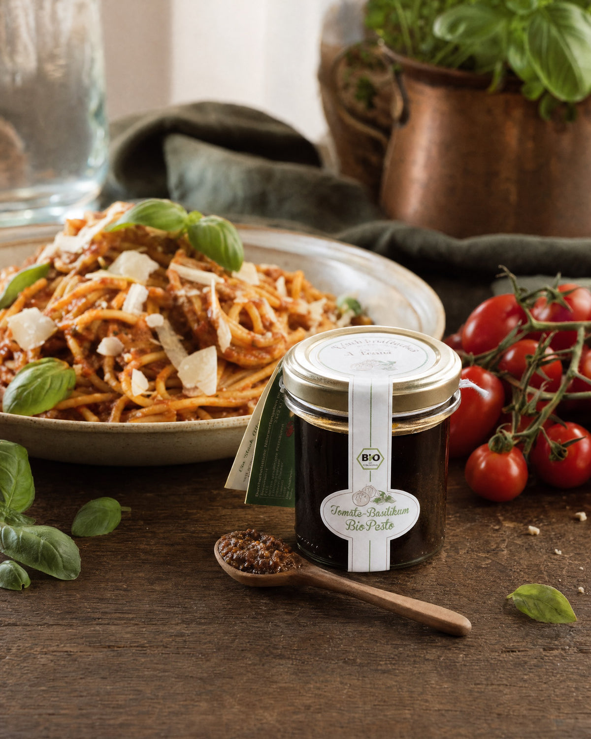 sell g'machts Tomate Basilikum Bio Pesto neben einem Teller Spaghetti mit Tomatenpesto, Kirschtomaten und Basilikum